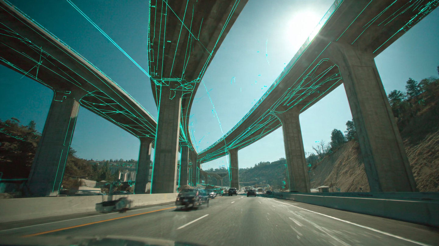 Dashcam view approaching a highway bridge with engineering deflection measurement overlay