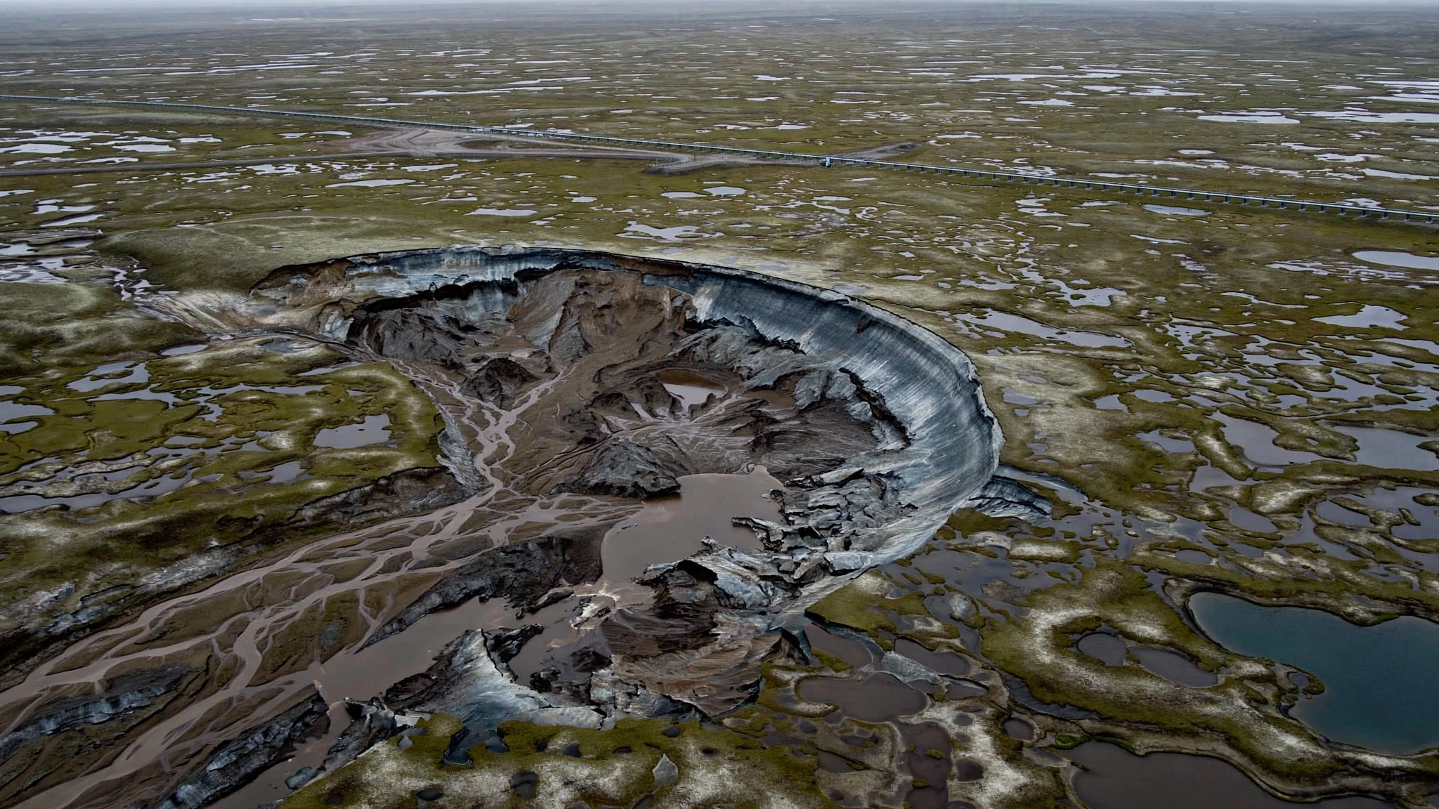 Aerial view of retrogressive thaw slumps scarring the permafrost tundra of the Yamal Peninsula, with exposed dark earth against white frozen terrain